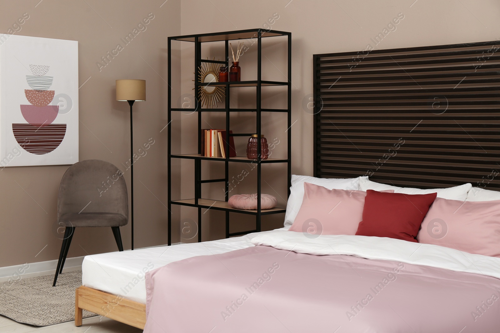 Photo of Large comfortable bed near beige wall in room. Interior design