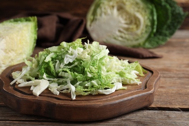 Photo of Cut fresh savoy cabbage on wooden table, closeup