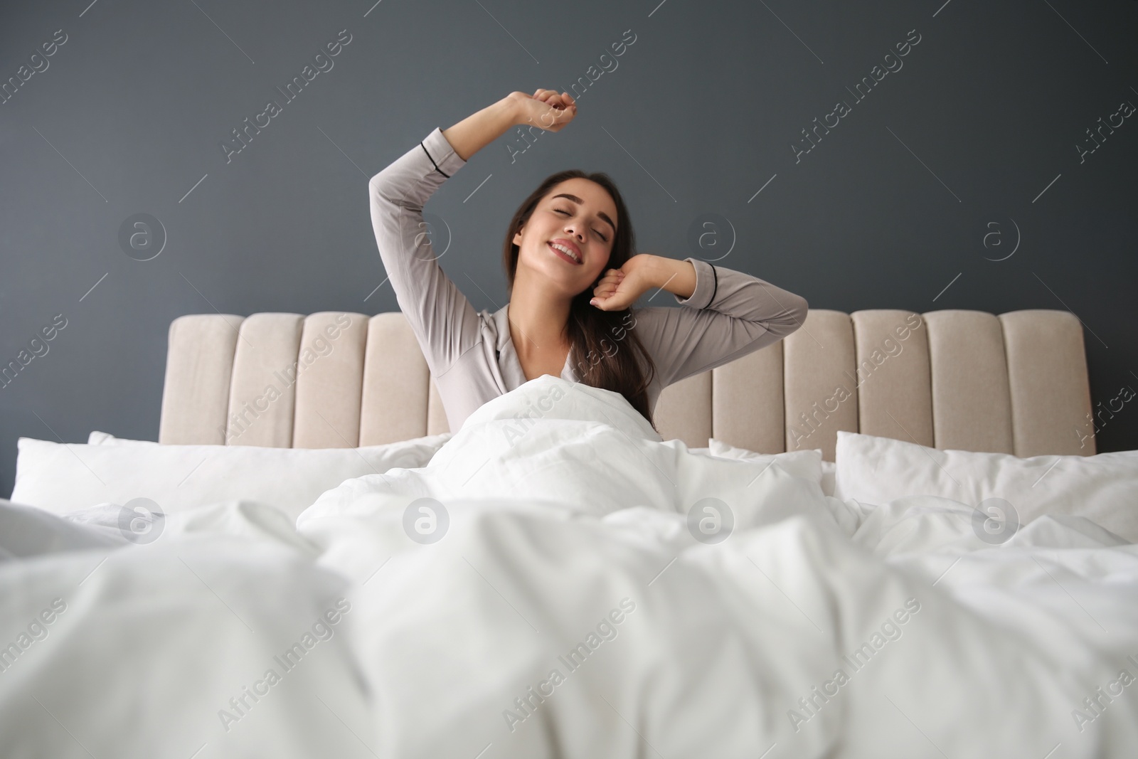 Photo of Beautiful young woman wrapped with soft blanket relaxing on bed at home