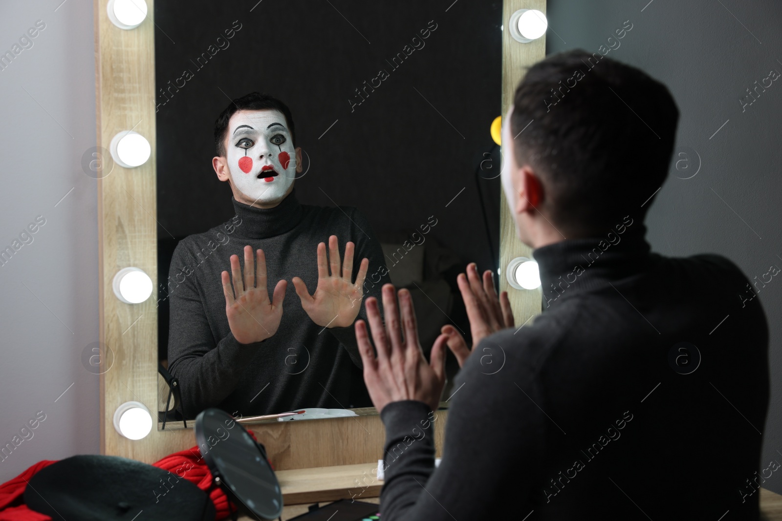 Photo of Mime artist posing near mirror in dressing room