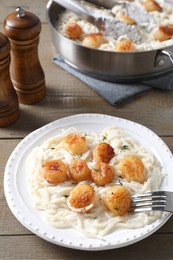 Photo of Delicious scallop pasta served on wooden table