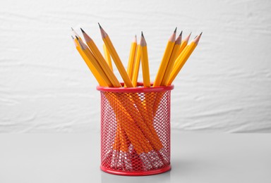 Photo of Many sharp pencils in holder on white background