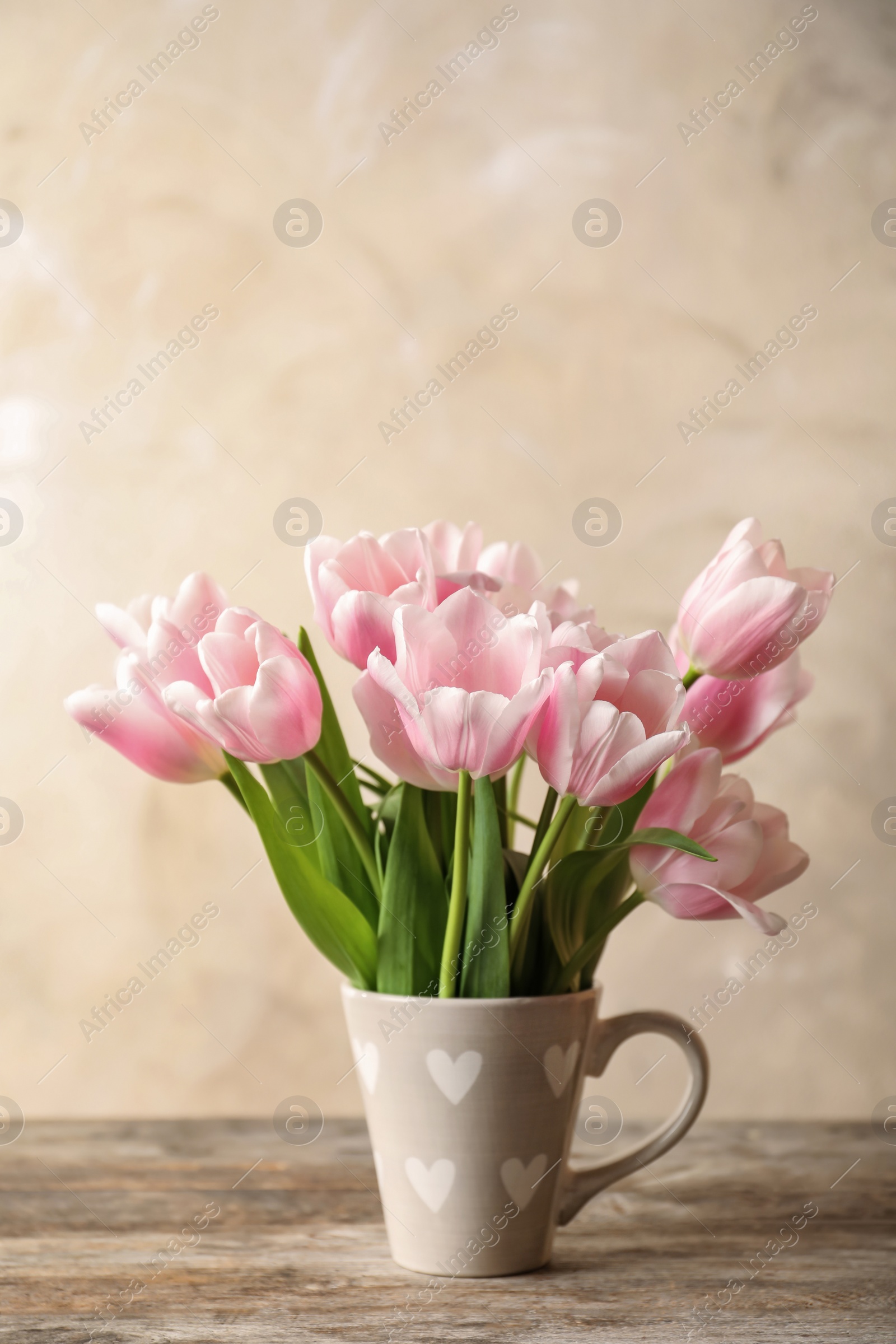 Photo of Cup with beautiful tulips for Mother's Day on table