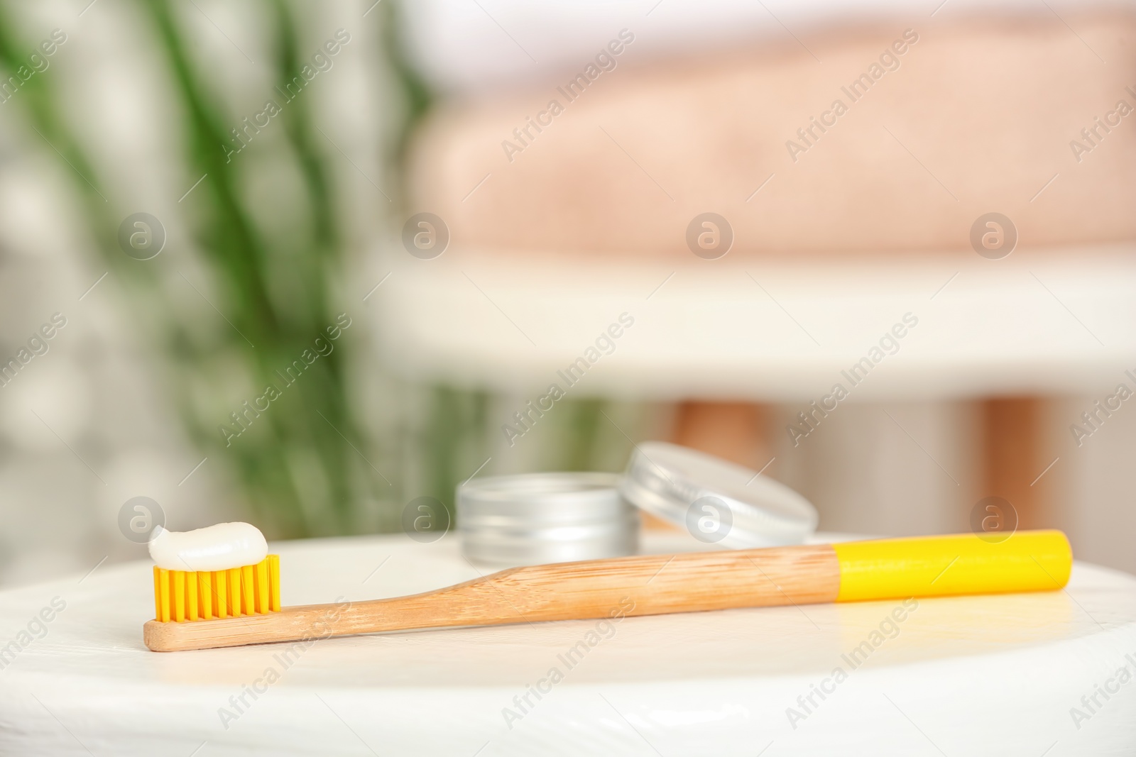 Photo of Bamboo toothbrush with paste on table against blurred background