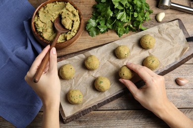 Woman making falafel balls at wooden table, top view