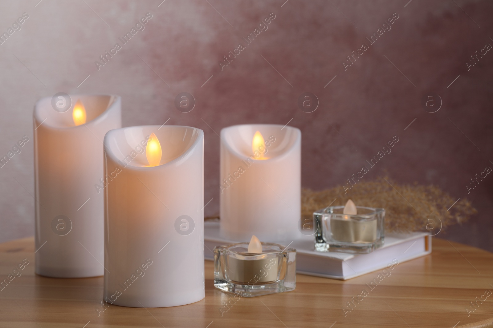 Photo of Glowing decorative LED candles on wooden table