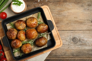 Photo of Delicious hot baked potato with sour cream on wooden background, flat lay