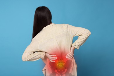 Image of Arthritis symptoms. Young woman suffering from pain in back on light blue background
