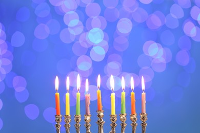 Photo of Hanukkah celebration. Menorah with burning candles against blurred lights
