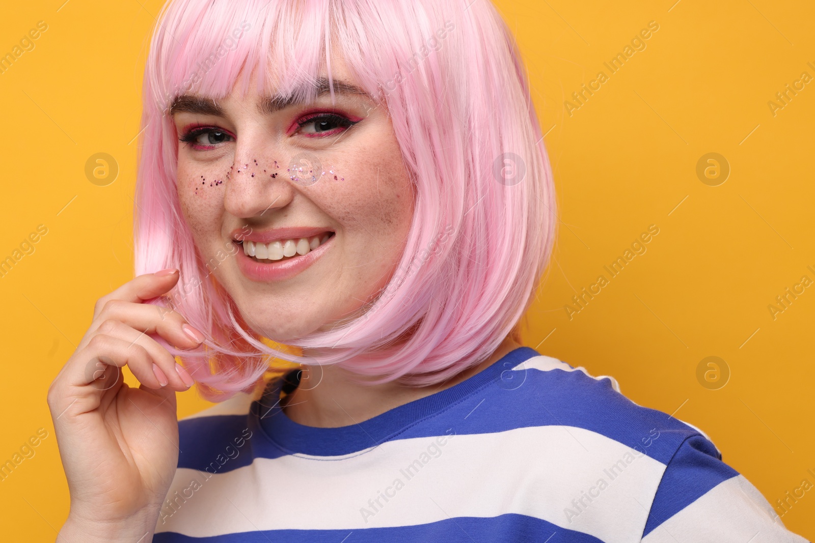 Photo of Smiling woman with bright makeup and glitter freckles on yellow background, closeup