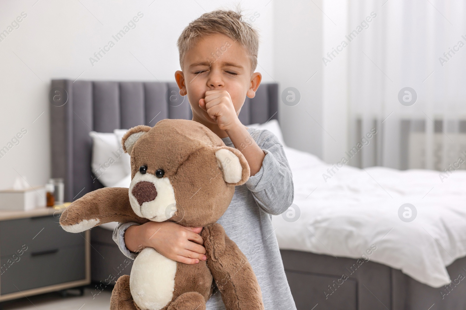 Photo of Sick boy with teddy bear coughing at home