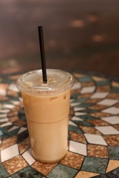 Photo of Takeaway plastic cup with cold coffee drink and straw on table outdoors