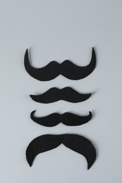 Fake paper mustaches on grey background, flat lay