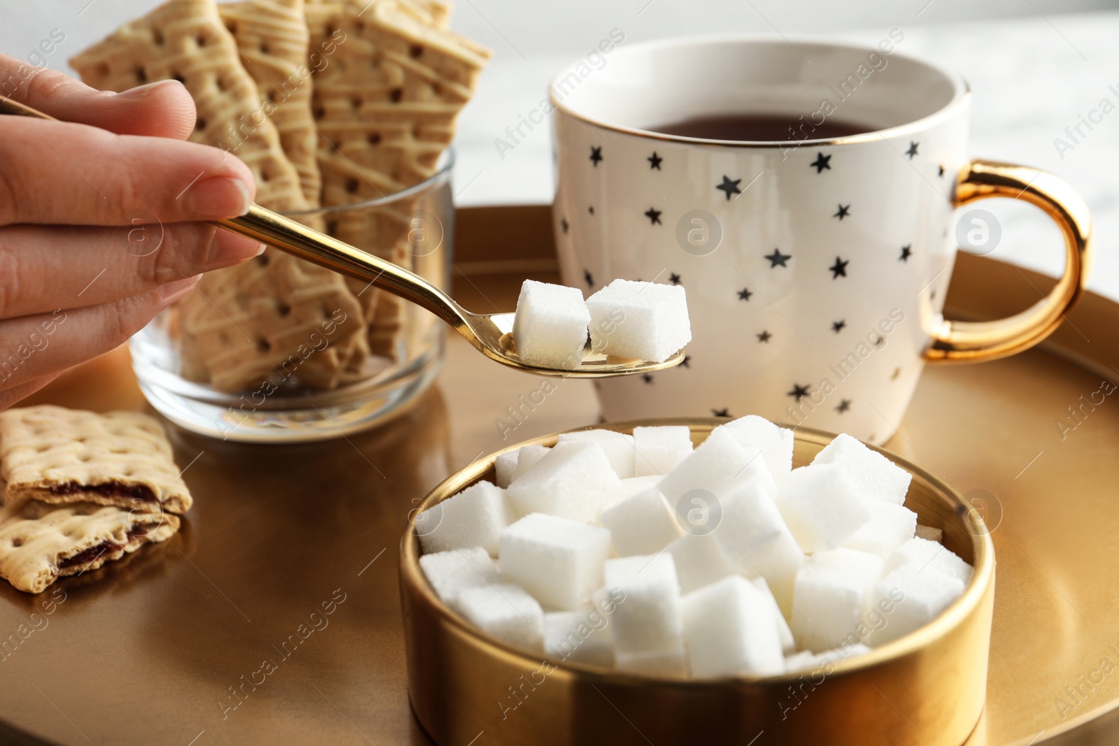 Photo of Woman taking sugar cubes from bowl at table, closeup