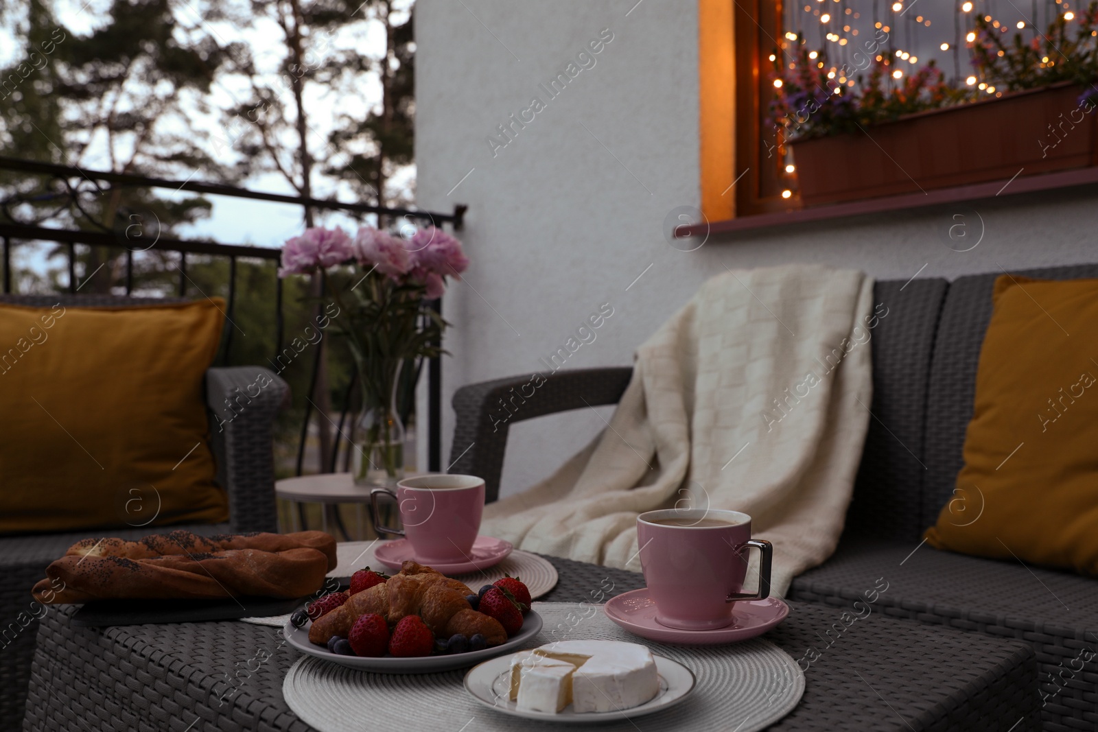 Photo of Rattan table with drink and food on outdoor terrace in evening