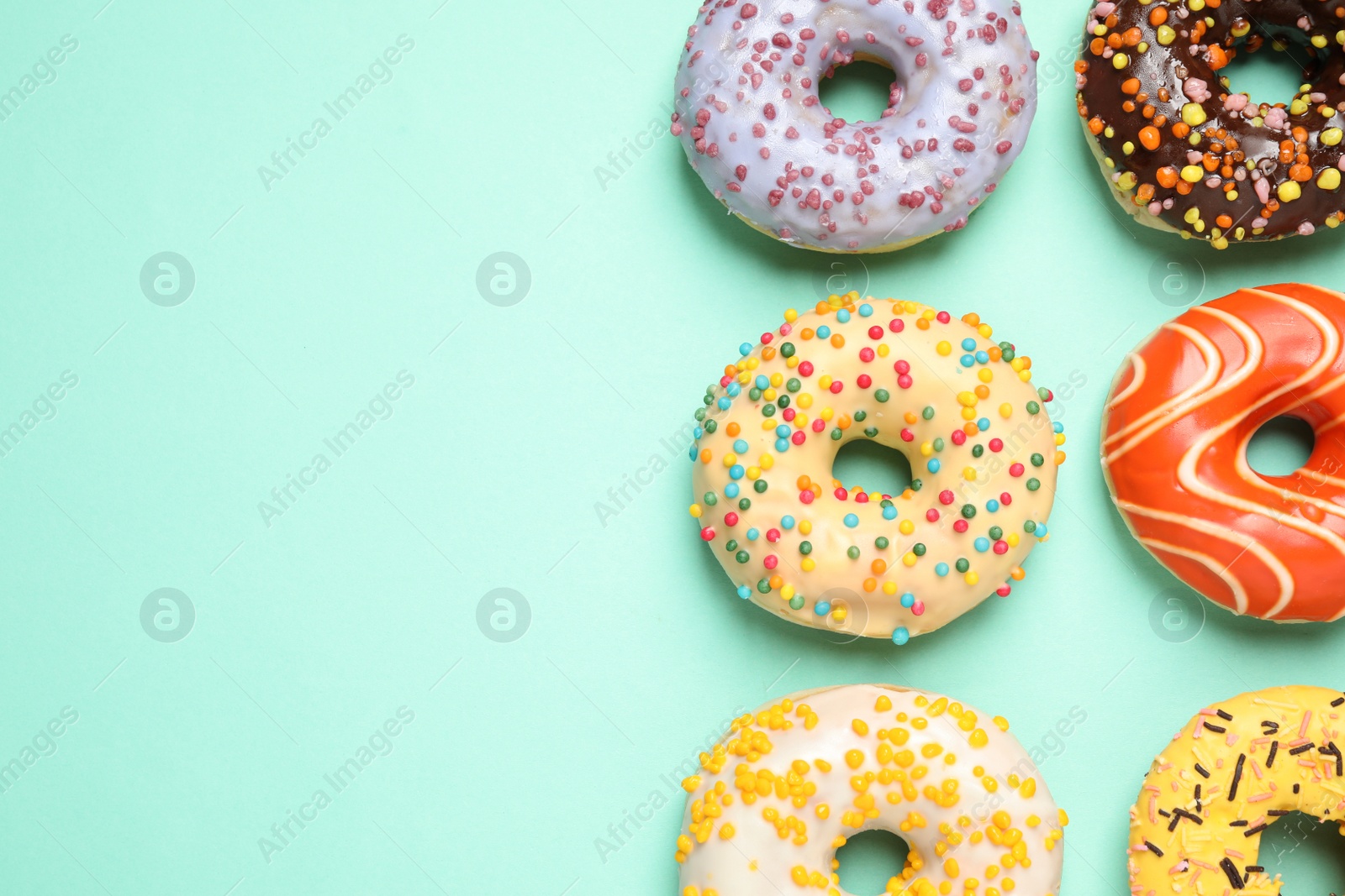 Photo of Delicious glazed donuts on turquoise background, flat lay. Space for text