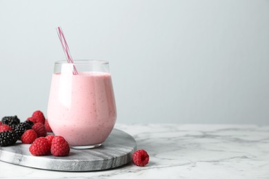 Image of Yummy berry smoothie in glass on white marble table, space for text 
