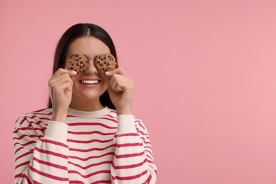 Photo of Young woman with chocolate chip cookies on pink background, space for text