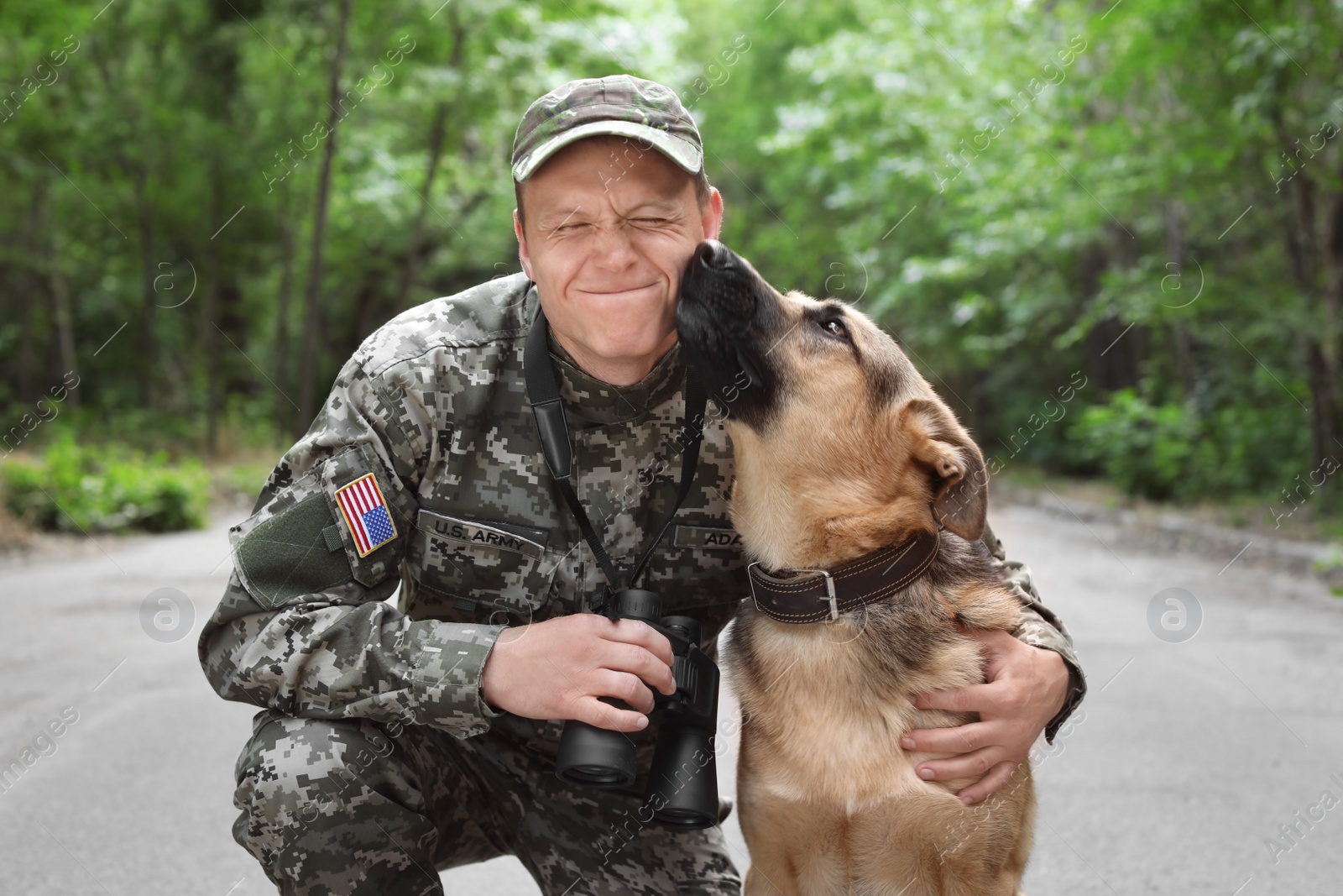 Photo of Man in military uniform with German shepherd dog, outdoors