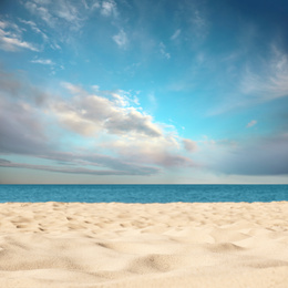 Image of Sandy beach near sea under blue sky with clouds