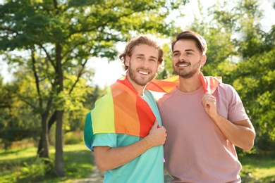 Photo of Happy gay couple with rainbow flag outdoors