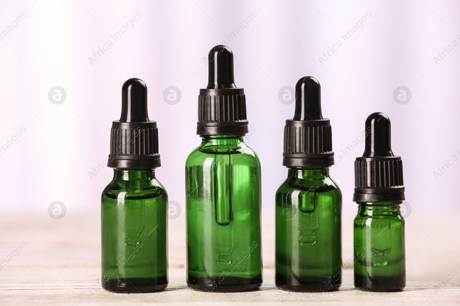 Photo of Bottles of essential oils on table against light background. Cosmetic products