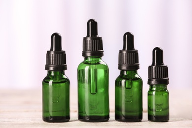 Bottles of essential oils on table against light background. Cosmetic products
