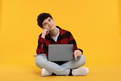 Photo of Portrait of student with laptop and pen on orange background