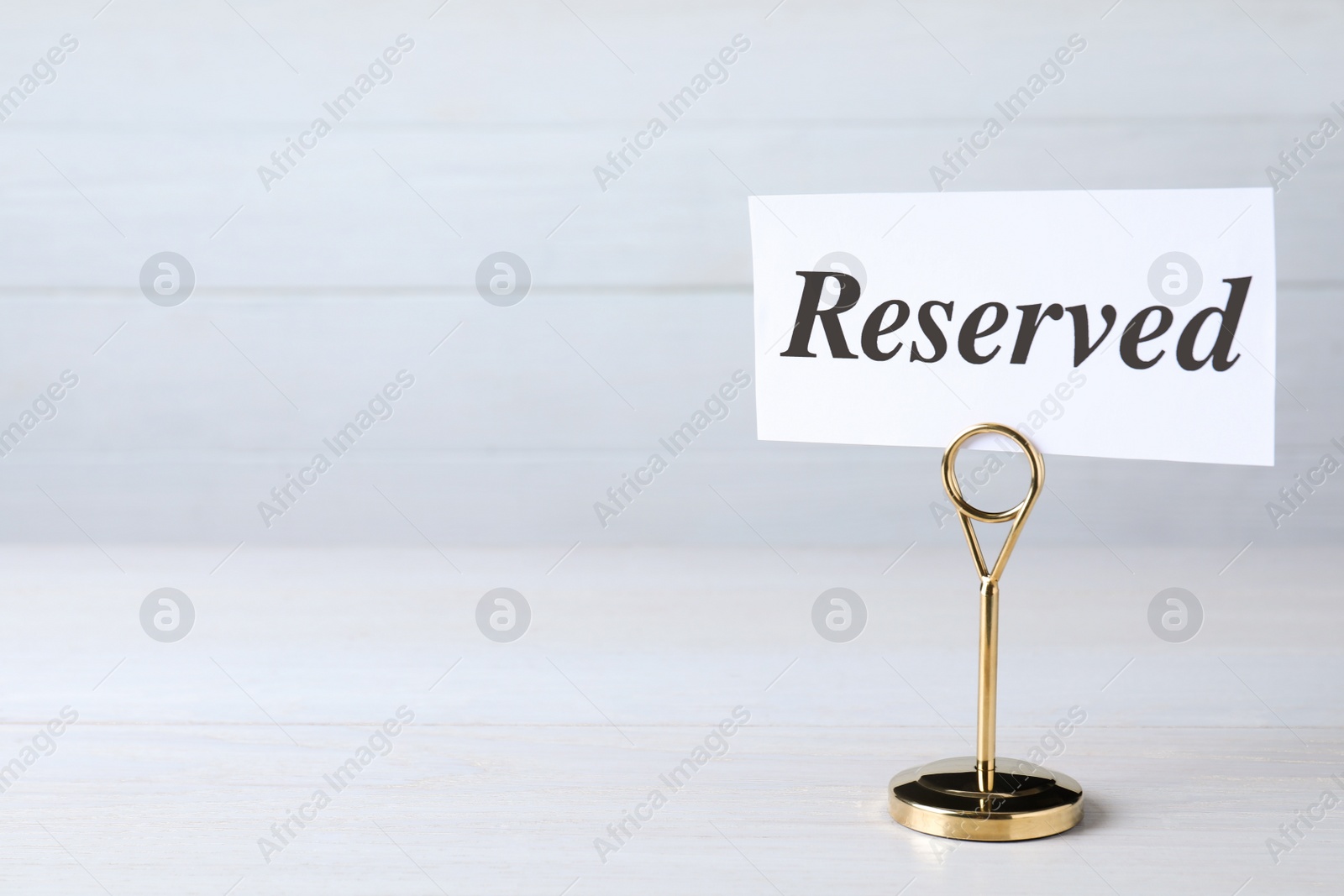 Photo of Elegant sign RESERVED on white wooden surface, space for text. Table setting element