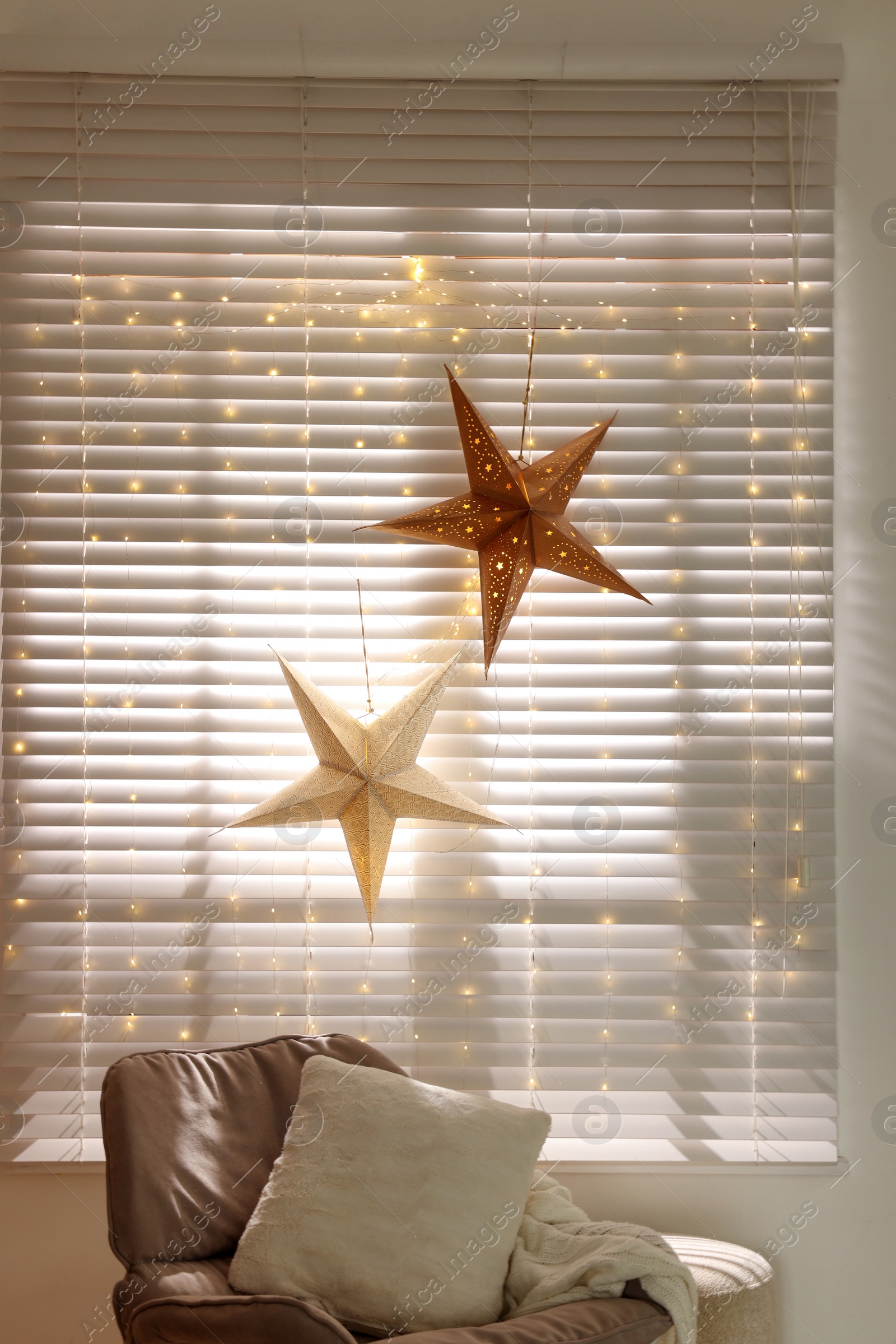 Photo of Beautiful decorative stars and festive lights in room. Christmas atmosphere