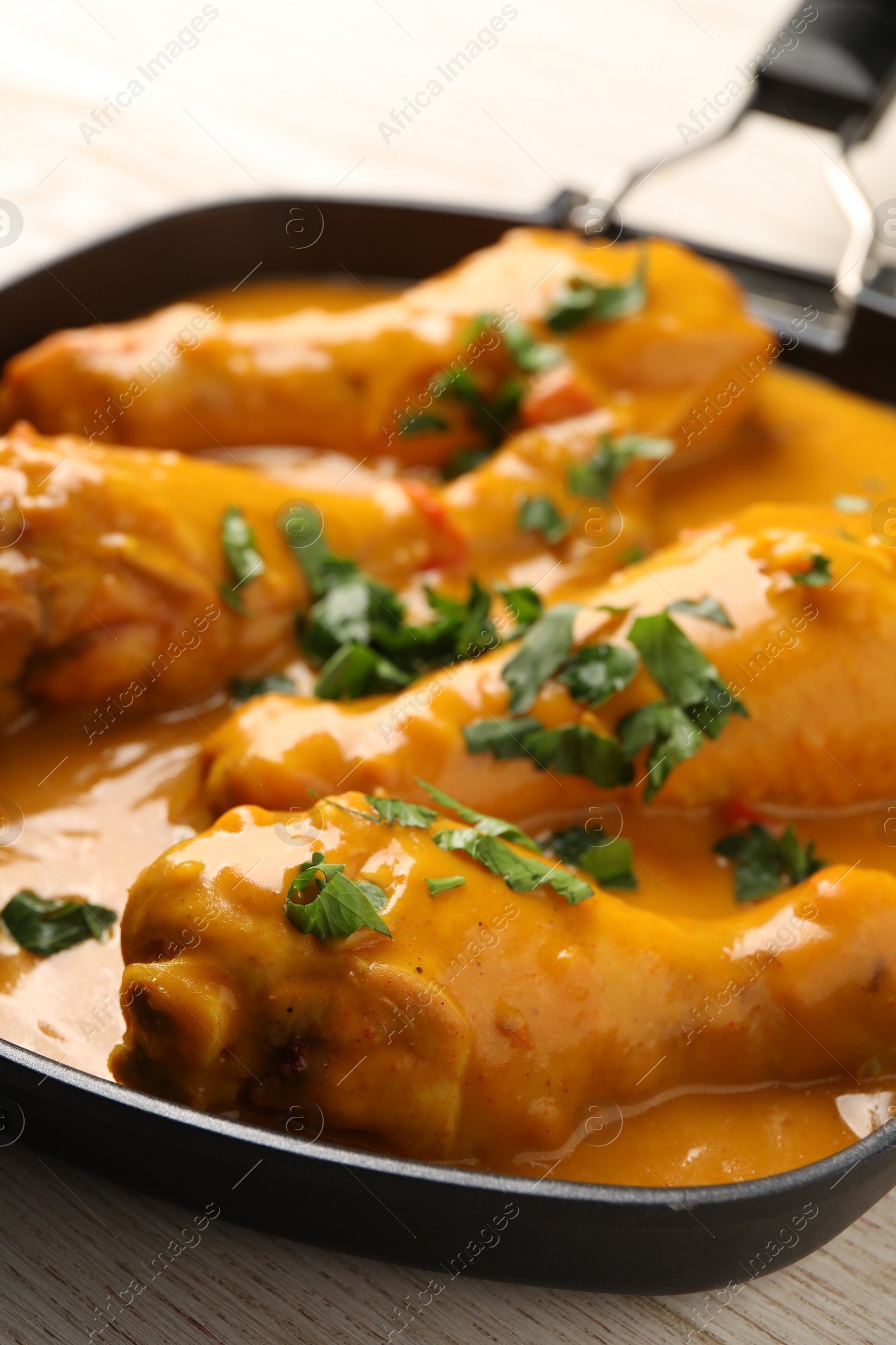 Photo of Tasty chicken curry with parsley on wooden table, closeup