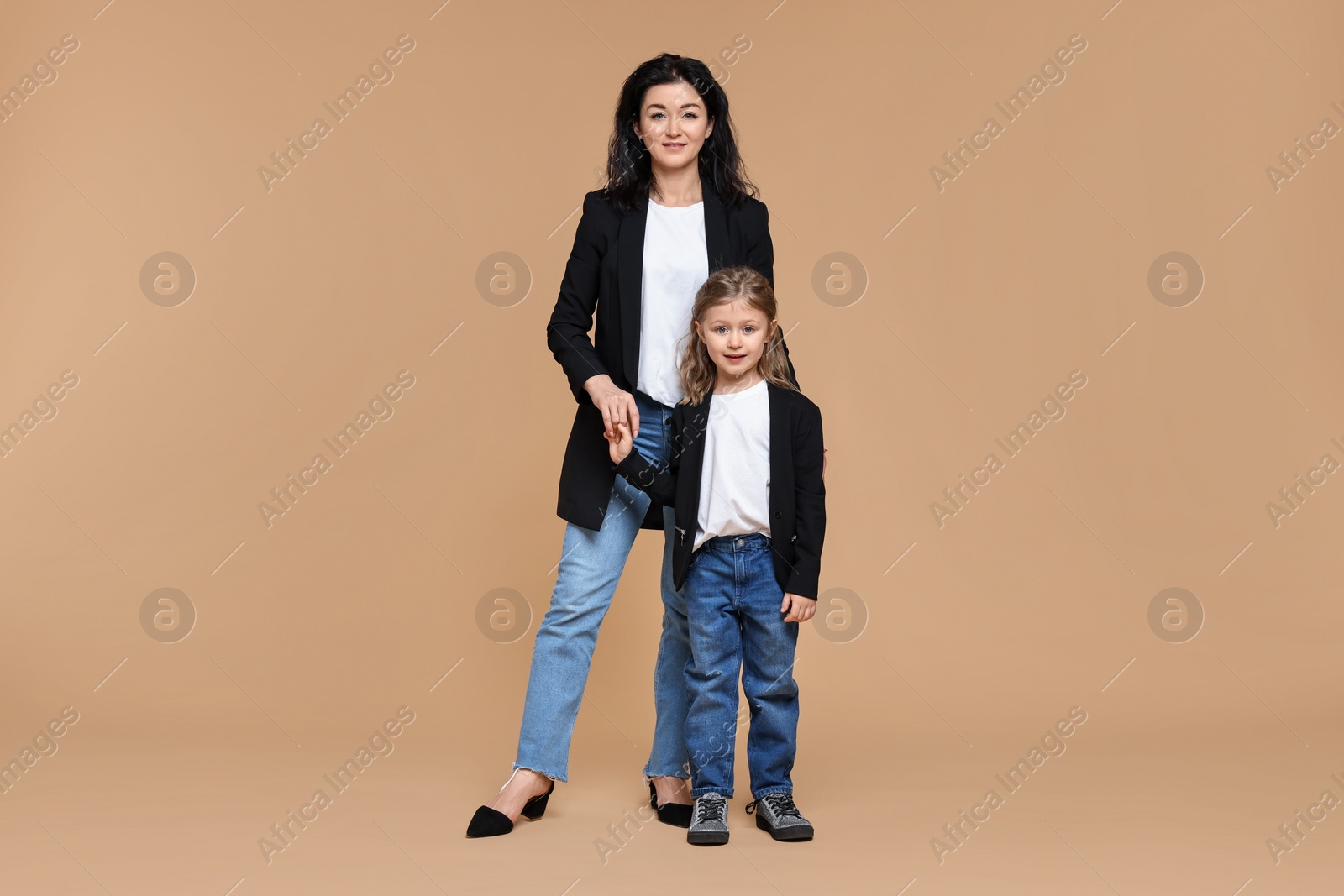 Photo of Beautiful mother with little daughter on beige background