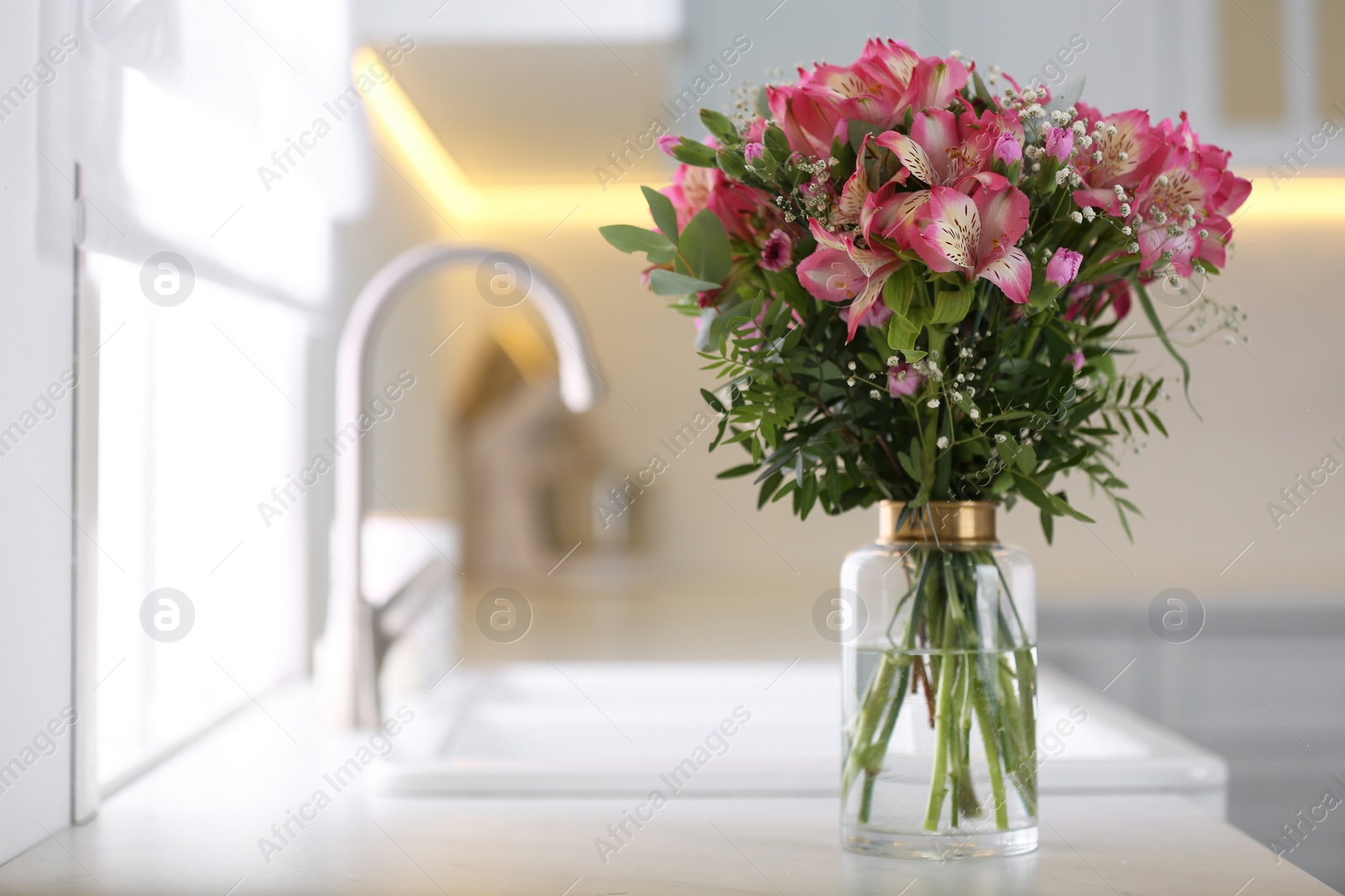 Photo of Vase with beautiful alstroemeria on countertop in kitchen, space for text. Interior design