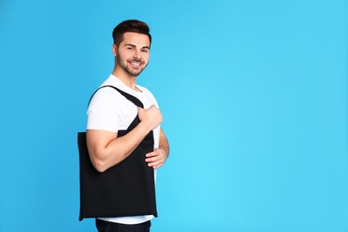 Portrait of young man with eco bag on blue background. Space for text