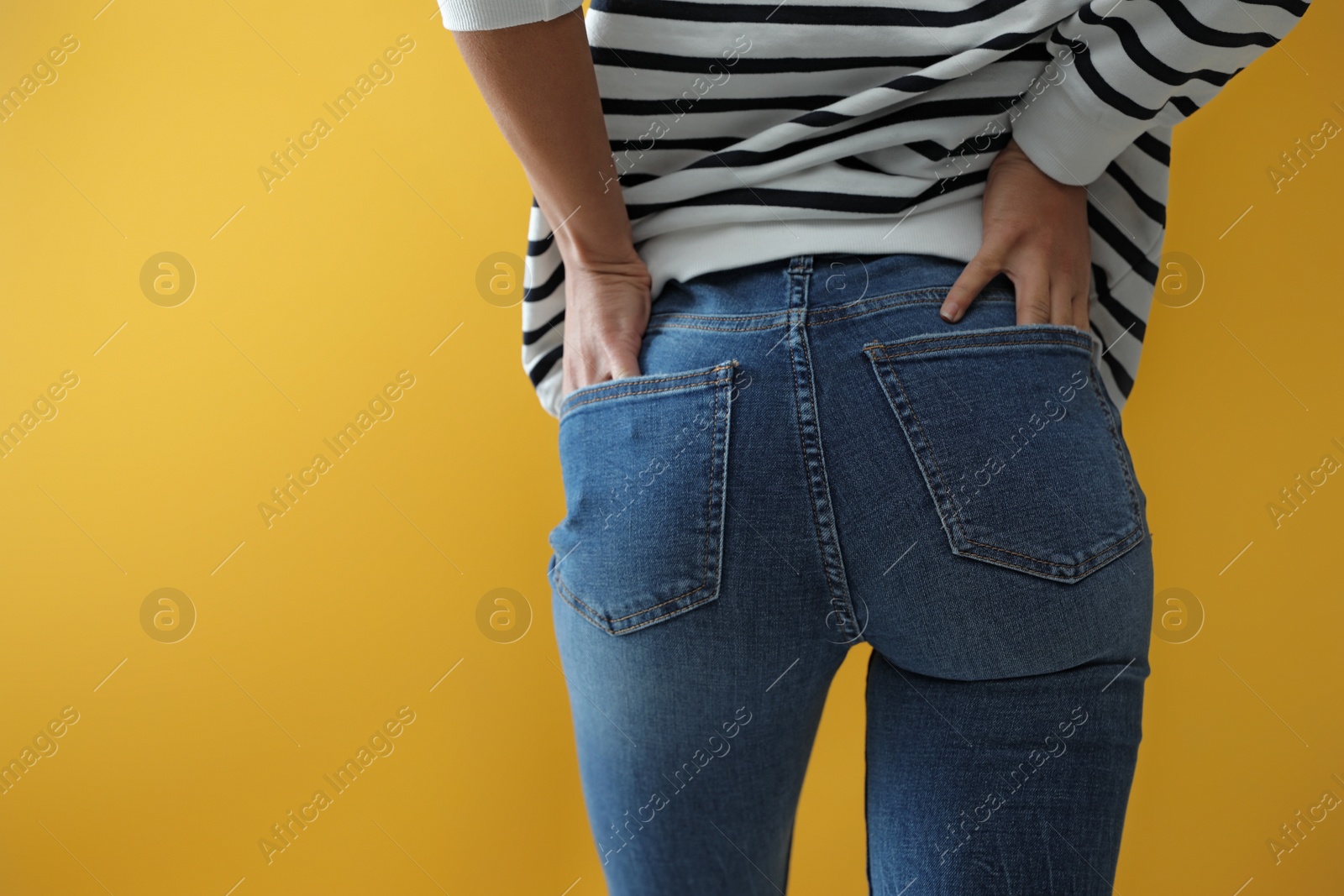 Photo of Woman wearing jeans on yellow background, closeup