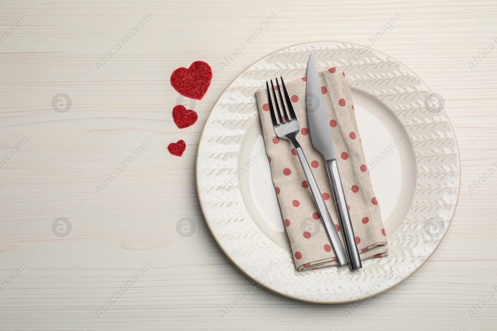 Photo of Plate with cutlery and decorative hearts on white wooden table for romantic dinner, top view. Space for text