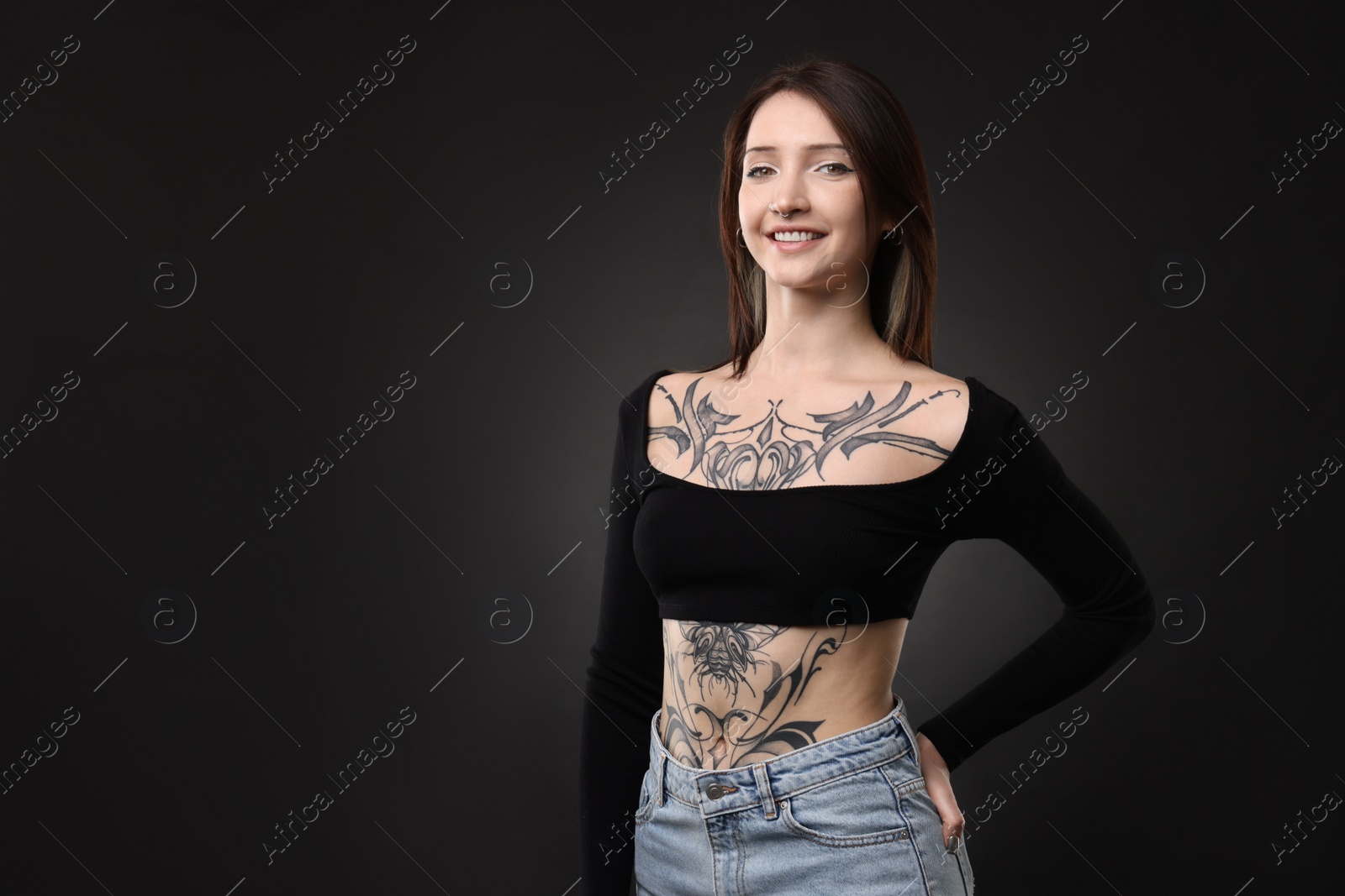 Photo of Portrait of smiling tattooed woman on black background. Space for text