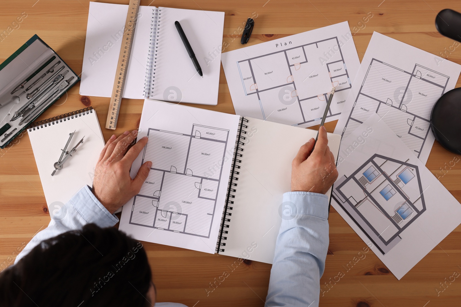 Photo of Man with sketchbook and pencil at wooden table, top view