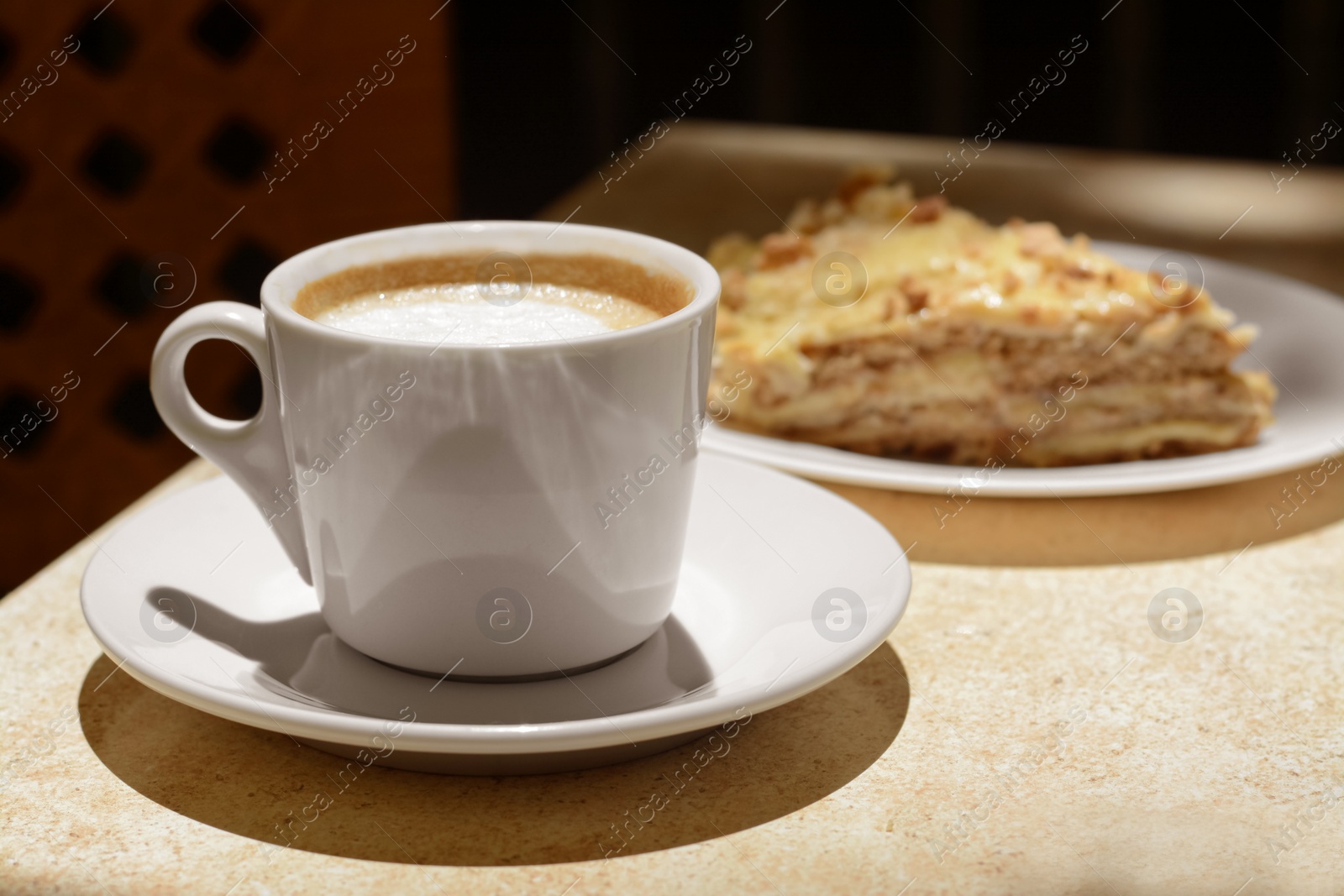 Photo of Cup of coffee and delicious cake on beige table, closeup