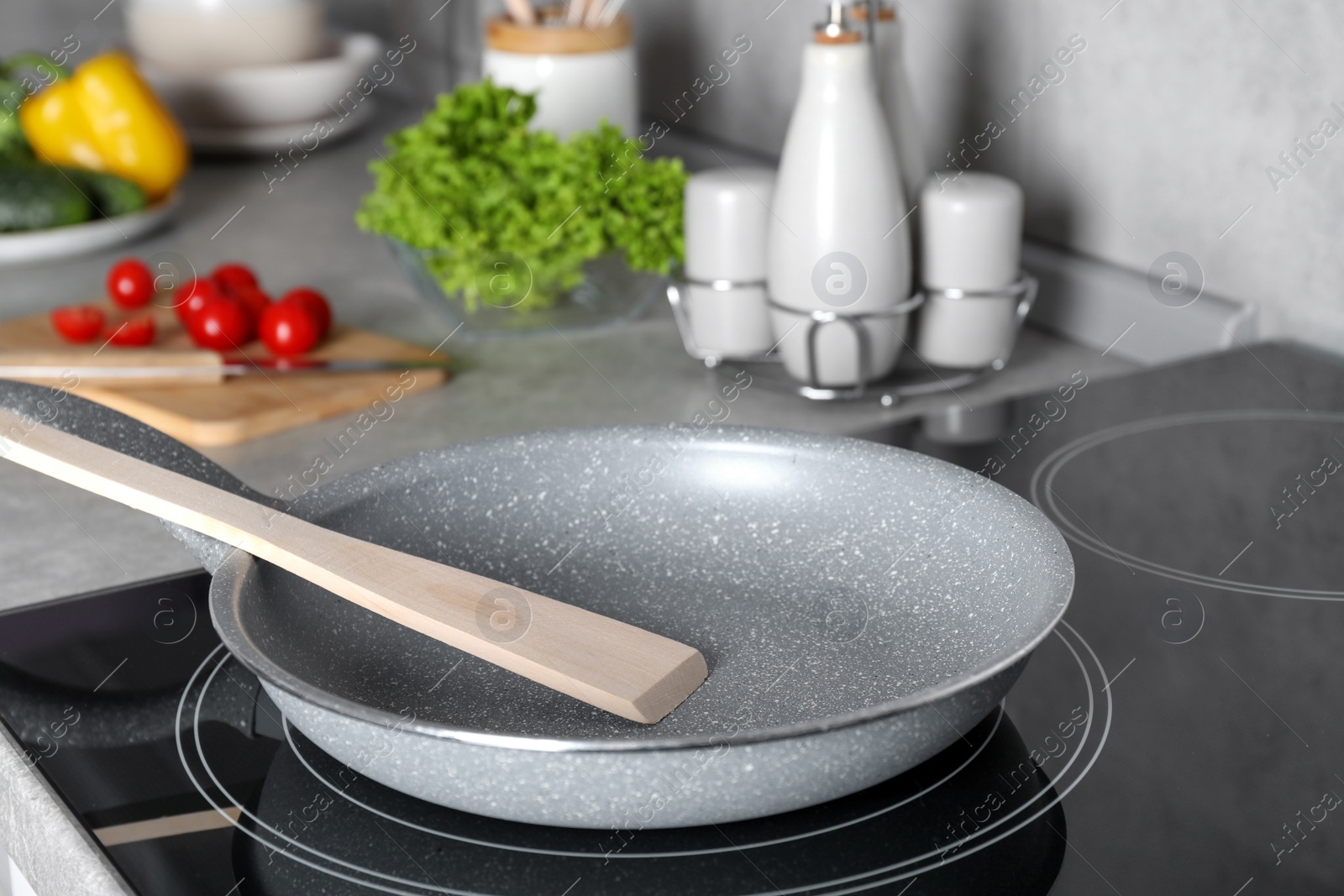 Photo of Frying pan with spatula on cooktop in kitchen. Cooking utensils