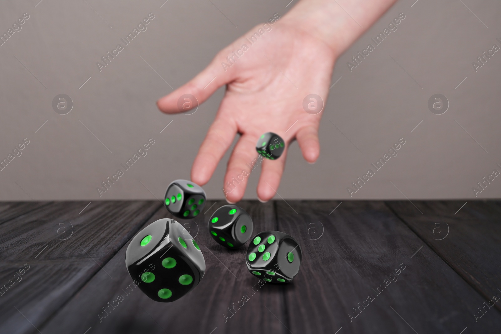 Image of Woman throwing dice on black wooden table, closeup