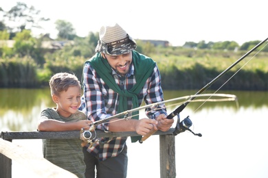 Photo of Father and son fishing together on sunny day