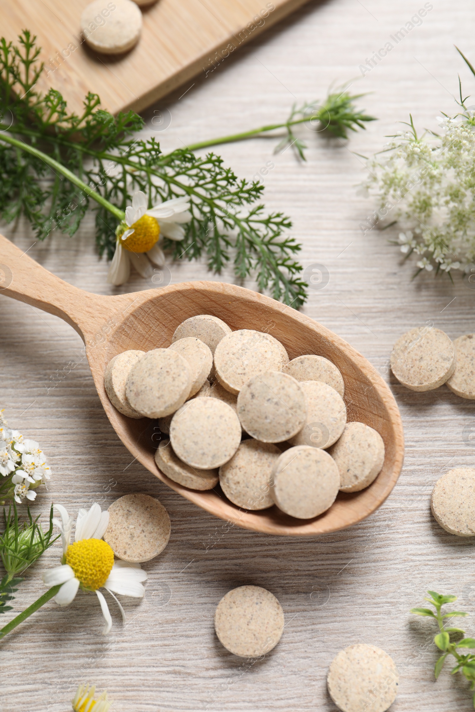 Photo of Pills, herbs and flowers on wooden table, flat lay. Dietary supplements