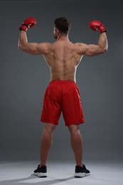 Photo of Man in boxing gloves on grey background, back view