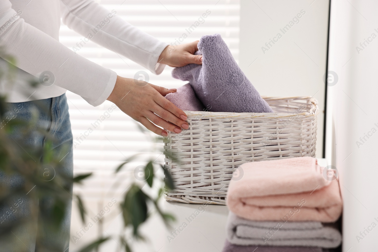 Photo of Woman with laundry basket of clean towels indoors, closeup