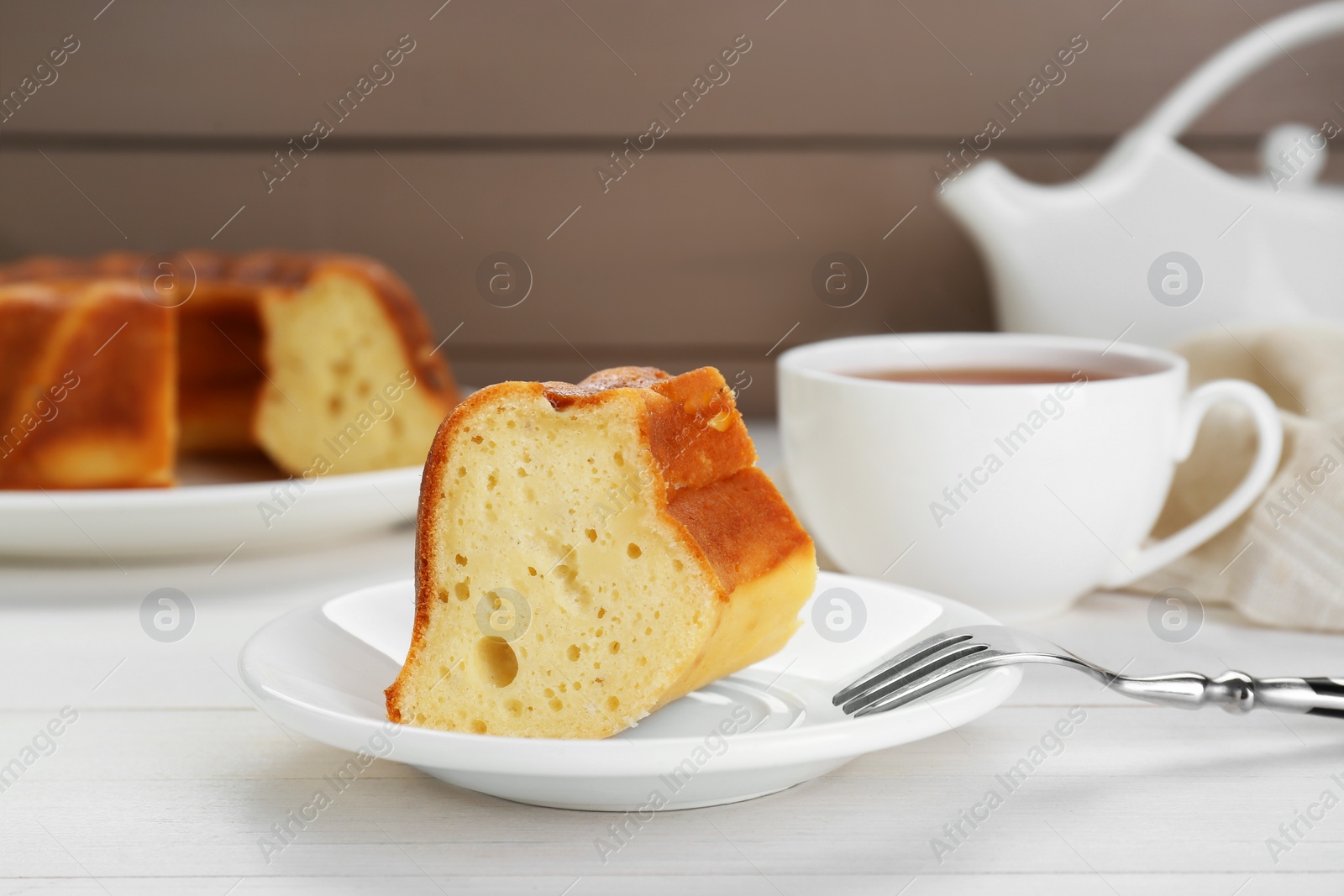 Photo of Piece of delicious homemade yogurt cake served on white wooden table