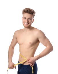 Portrait of young man with measuring tape showing his slim body on white background