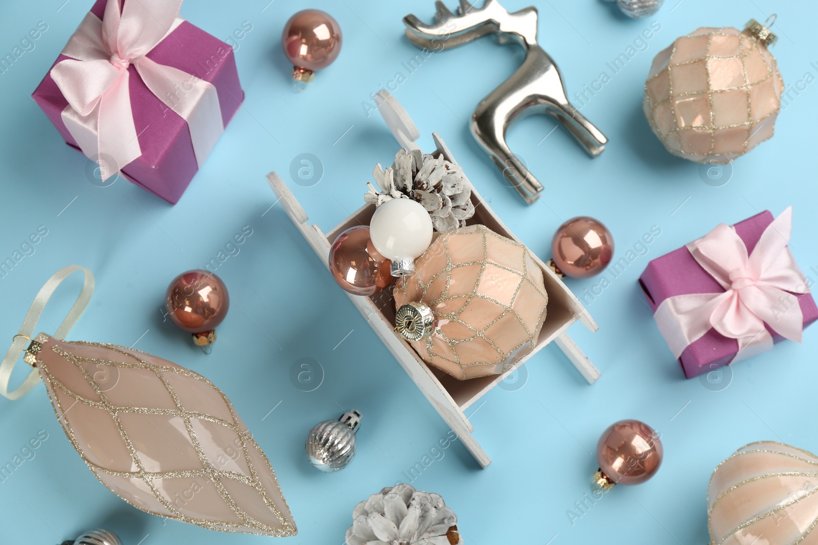 Photo of Beautiful Christmas composition with miniature sleigh on light blue background, flat lay