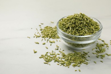 Photo of Fennel seeds in bowl on white table, closeup. Space for text