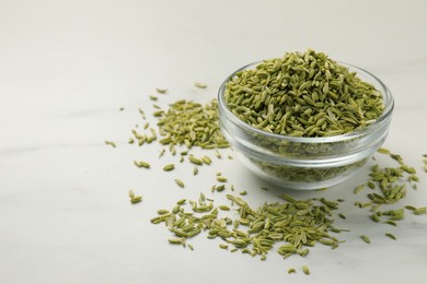 Fennel seeds in bowl on white table, closeup. Space for text